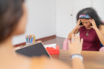 Woman looking down with hands on head during psychological therapy