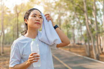 Young woman wiping off her sweat after her morning run at a local running park