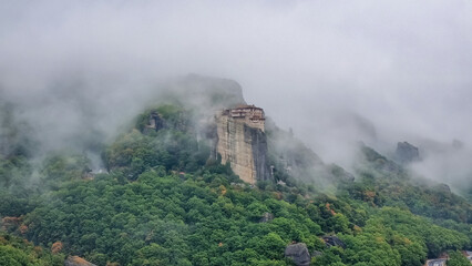 Panoramic view of Holy Orthodox Monastery of Rousanou (St. Barbara), Kalambaka, Meteora, Thessaly, Greece, Europe. Unique rock formation are surrounded by mystical fog. Moody dramatic atmosphere