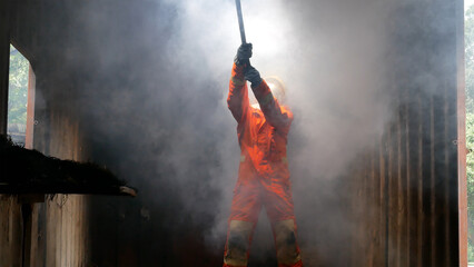 Firefighter fighting with flame using fire hose chemical water foam spray engine. Fireman wear hard...