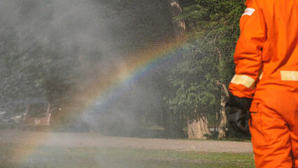 Firefighter fighting with flame using fire hose chemical water foam spray engine. Fireman wear hard...