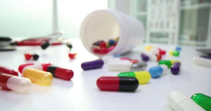 Red capsules and tablets sprinkled into white bottles on table