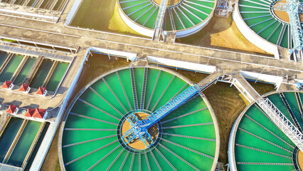 Aerial view of a wastewater treatment plant showcases its industrial might - massive tanks, pumps,...