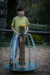 A young boy is playing on a children's playground in the park