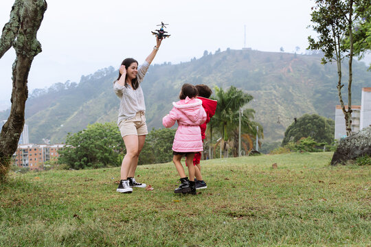 International Children Day. Latina mother having fun with her children outdoors, jumping and running. Family day. Concept of love and togetherness. Single mother of two young children.