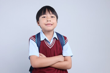 Portrait of Asian student little boy wearing backpack looking at camera confidently with arms crossed