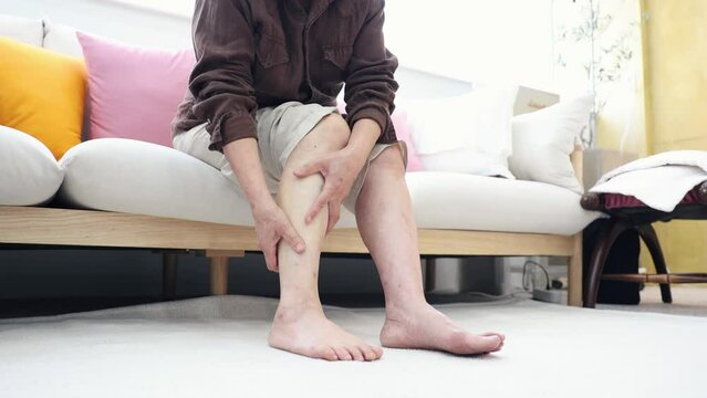 Grandmother massaging her sore calf due to numbness in her legs