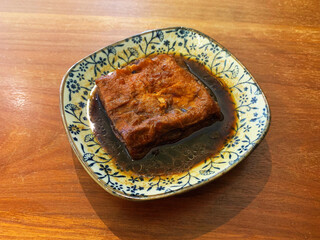 signature traditional square braised tofu bean curd ru dou fu with dark soy sauce in plate on wood background asian halal food restaurant banquet vegan cuisine menu for cafe design