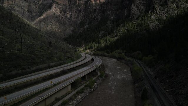 Aerial tilt down on highway I70 through Glenwood Canyon Colorado next to Colorado River and train track