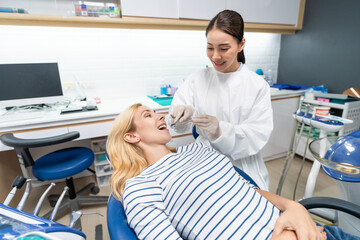 Female dentist examine tooth to Caucasian girl at dental health clinic. 