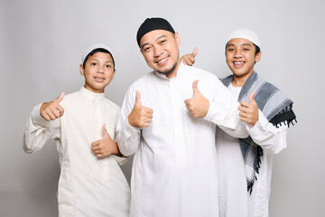 Cheerful muslim dad and children in white robe showing thumbs up