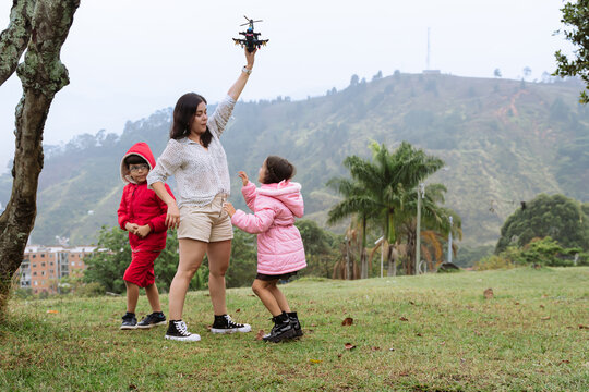 International Children Day. Latina mother having fun with her children outdoors, jumping and running. Family day. Concept of love and togetherness. Single mother of two young children.