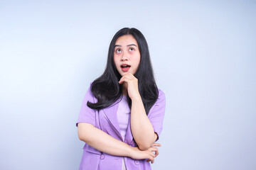 Young Asian woman put hand on chin and looking up have a good idea isolated on grey background