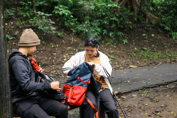 Couple sits in forest, checking bag and take a rest 