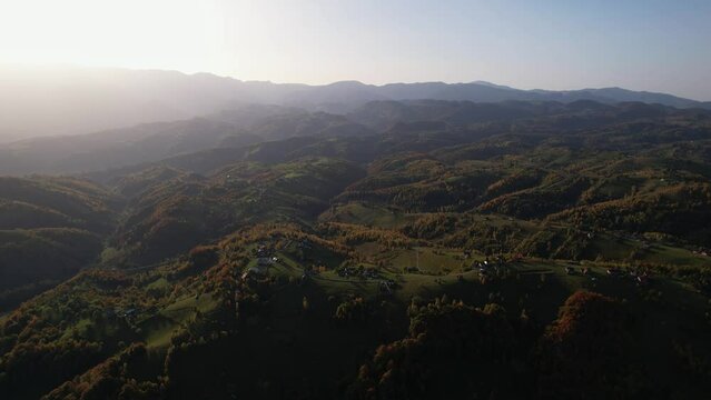 Pestera village in brasov at sunset with rolling hills and scattered houses, aerial view
