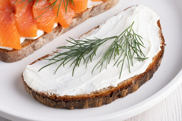 Rye sandwich with cream cheese and salmon on white wooden table