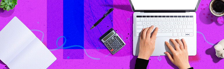 Woman using a laptop computer with a piggy bank and a calculator