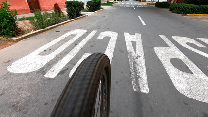 Perspective shot of a cyclist's wheel approaching a stop sign on the road, signaling caution