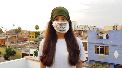 Thoughtful woman wears a mask with a text about the pandemic, standing in a cityscape