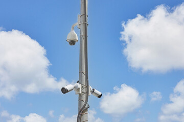 CCTV cameras are installed in the park on a power line pole, against the blue sky.
