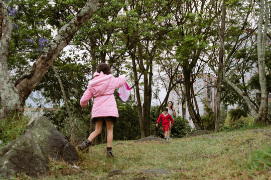 International Children Day. Latina mother having fun with her children outdoors, jumping and running. Family day. Concept of love and togetherness. Single mother of two young children.