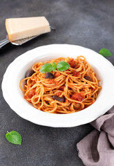 Spaghetti alla puttanesca or Neapolitan pasta on a gray background. Italian Cuisine. 