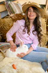 Woman in pink shirt playing with a white bunny rabbit