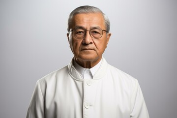 Obraz premium Headshot of a serious looking elderly Asian man wearing glasses and a white lab coat