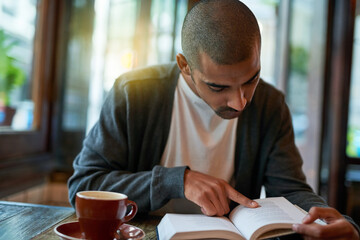 Man, coffee and reading book at cafe in table with novel or story for knowledge. Restaurant,...