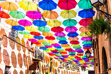 Fototapeta na wymiar Background of many hanging colorful umbrellas decorating the street of a town