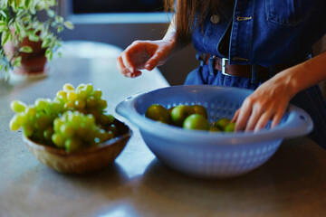 Woman holding a bowl of grapes in front of a table with assorted bowls of grapes, including green grapes