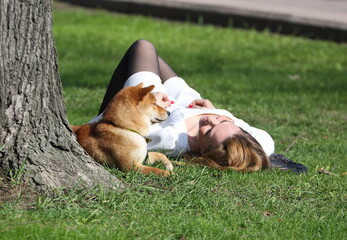 A girl with a dog lying on the grass of the lawn, Alexander Garden, St. Petersburg, Russia, April...
