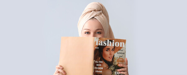 Pretty young woman after shower reading magazine on light background