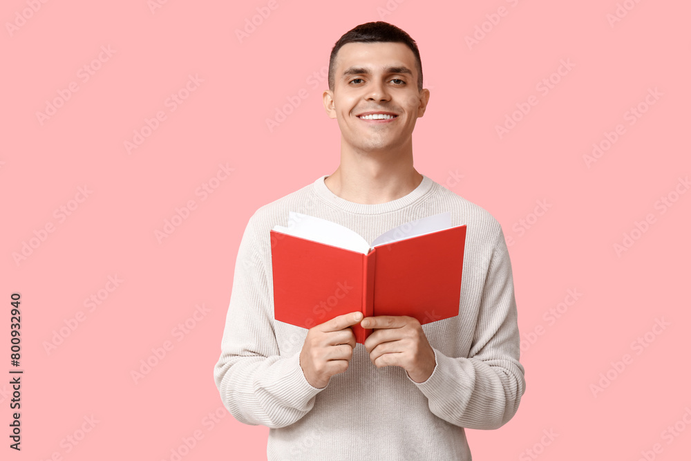 Poster handsome young man reading book on pink background