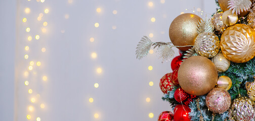 A Christmas tree decorated for the new year with toys and bows on a festive background. An elongated panoramic image for a banner in red white and gold colors