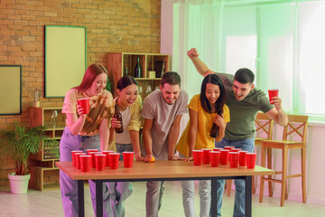 Group of young friends playing beer pong at party - obrazy, fototapety, plakaty