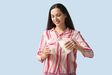 Young woman with glass and bottle of tasty milk on blue background
