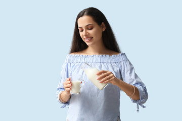 Young woman with glass and bottle of tasty milk on blue background - obrazy, fototapety, plakaty