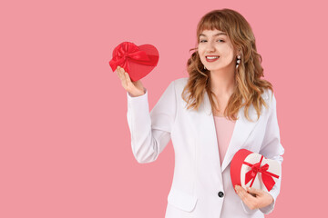 Beautiful young woman with gift boxes for Valentine's Day on pink background