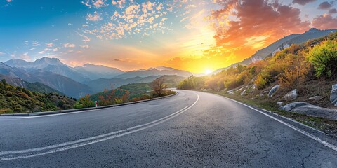 Sunrise over a scenic mountain landscape and a paved highway.