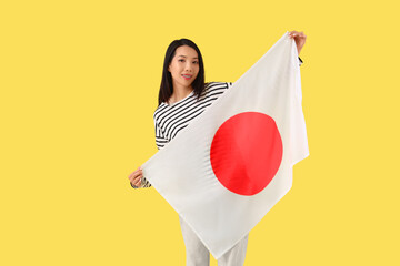 Young Asian woman with flag of Japan on yellow background