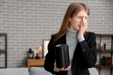 Mourning young woman with mortuary urn at home