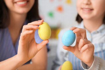 Little girl and her mother with painted Easter eggs at kitchen, closeup