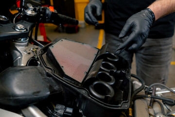 close up In a motorcycle repair shop mechanic removes a filter to replace it with a new one