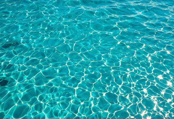 Beautiful turquoise blue ocean water surface with light reflections and highlights. Texture of water close-up macro
