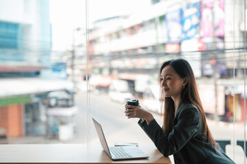 Young woman enjoying a cup of coffee alone in a cafe or bar and using smartphone.