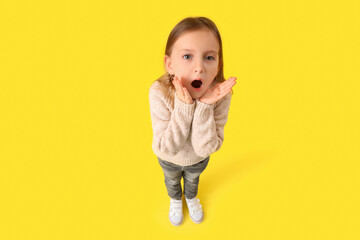 Shocked little girl on yellow background