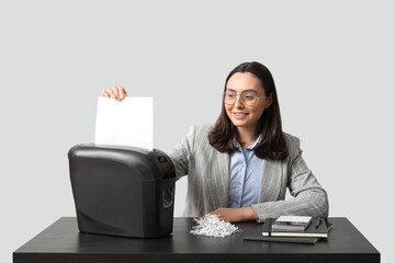 Secretary destroying document in shredder on light background - obrazy, fototapety, plakaty