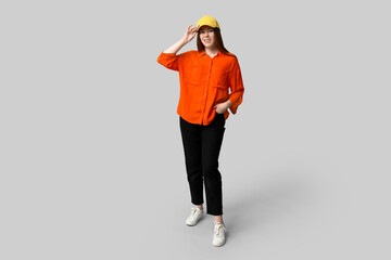 Stylish young girl in baseball cap and shirt on light background
