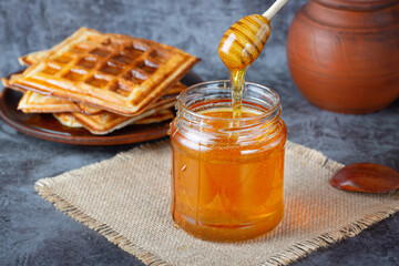 Honey in jar with honey dipper and belgian waffles